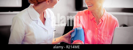 Female nurse checking blood pressure of senior woman Stock Photo
