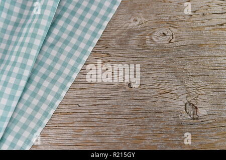 Mint and white is the checkered pattern on a tablecloth. The fabric lies in folds on old weathered wood. Stock Photo
