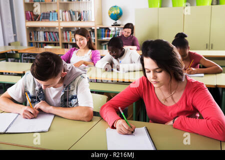 Portrait of positive multiethnic school pupils taking a lesson in the class Stock Photo