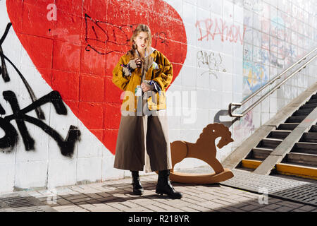 Fashion blogger standing near wall with graffiti wearing dark boots Stock Photo
