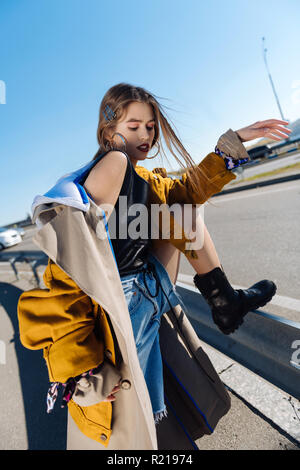 Dark-haired skinny model posing on the bridge on windy day Stock Photo
