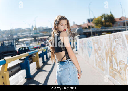 Stylish young woman wearing high-waist baggy jeans and leather top Stock Photo