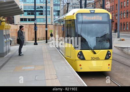 MANCHESTER, UK - APRIL 21, 2013: People board Manchester tram in Manchester, UK. Manchester Metrolink serves 21 million rides annually (2011). Stock Photo