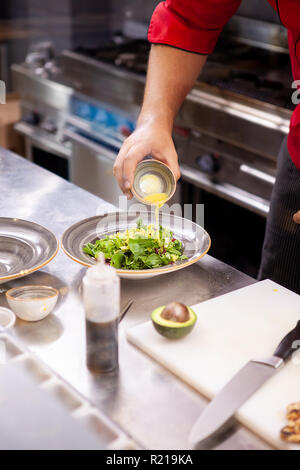 Chef seasoning delicious salade in his restaurant kitchen Stock Photo