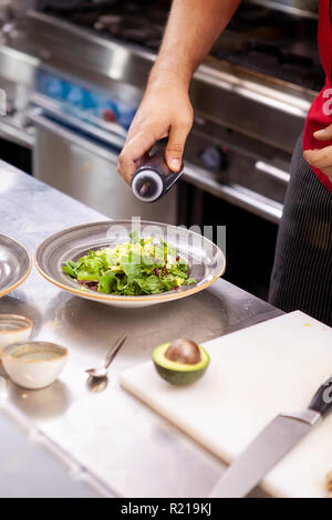 Chef seasoning delicious salade in his restaurant kitchen Stock Photo