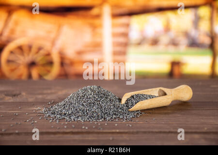 Lot of whole czech blue poppy seeds with wooden scoop with cart in background Stock Photo