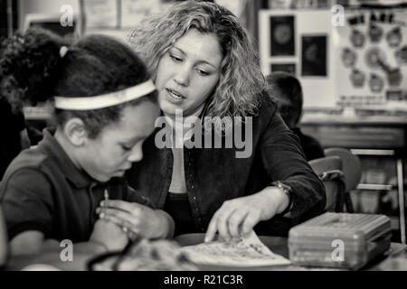 A teacher helping students in the class room at an elementary school Stock Photo