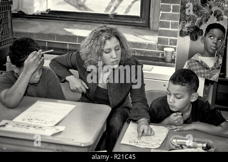 A teacher helping students in the class room at an elementary school Stock Photo