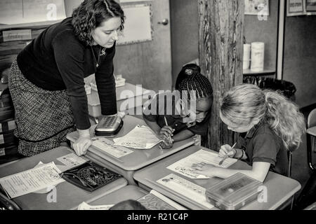 A teacher helping students in the class room at an elementary school Stock Photo