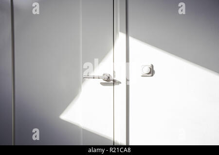 Close-up white door with sunlight. Chrome door ,The light switch on the wall modern design empty and clean Stock Photo