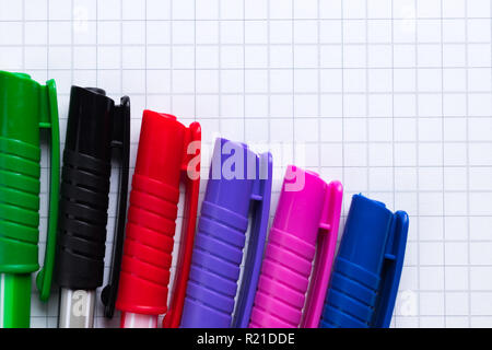 Colorful pens in a row on sheet of squared paper. Education abstract concept. Copy space on the top right corner. Stock Photo