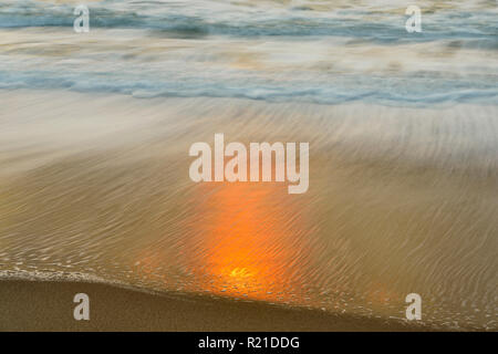 Surf and reflected sunlight on wet beach sand at sunset , Ventura , California, USA Stock Photo