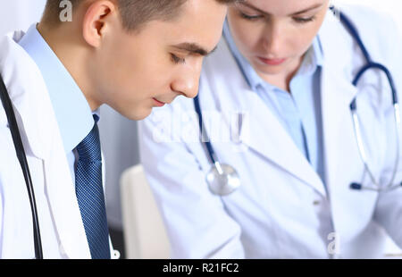 Doctors writing papers using clipboard. Physicians discussing medication program or studying at medical conference. Healthcare, insurance and medicine concept Stock Photo