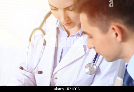 Doctors writing papers using clipboard. Physicians discussing medication program or studying at medical conference. Healthcare, insurance and medicine concept Stock Photo