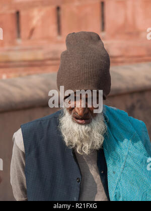 An elderly man with a big white beard against a background of red walls. India Agra 2012 Stock Photo