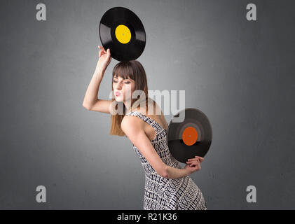 Young lady holding vinyl record on a grey background Stock Photo