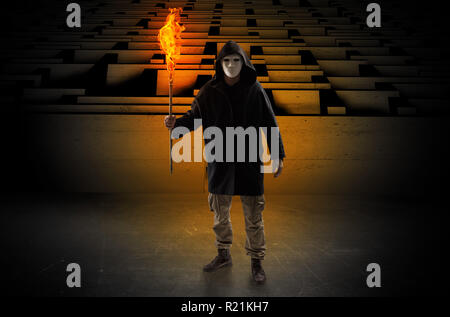 Ugly, aberrant man coming out from the labyrinth with burning flambeau on his hand  Stock Photo