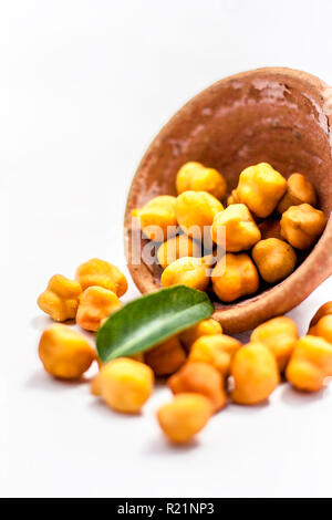 Raw bright dark brown colored Desi chana or original chickpea in a glass bowl isolated on white. Stock Photo