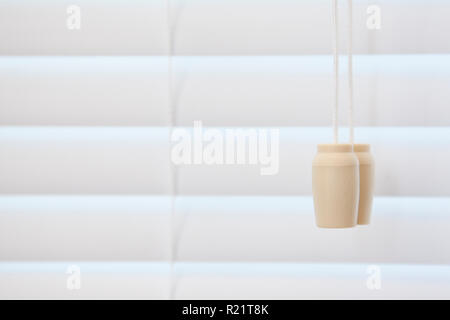 A string for pulling a blind open and closed beside a drawn shutter Stock Photo