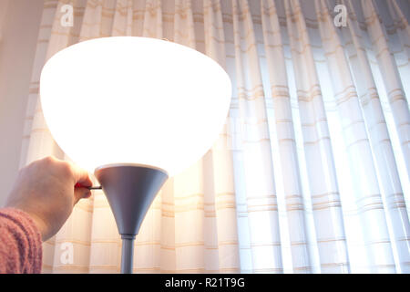 Hand turns the switch on a lamp Stock Photo