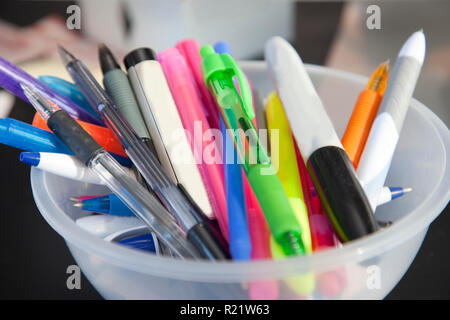 Pens, highlighters and permanent markers fill a bowl of writing utensils at home or office Stock Photo
