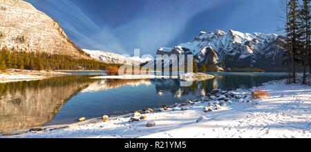 Wide Panoramic Scenic Landscape View Minnewanka Lake Shore and Distant Snowcapped Peaks after Autumn Snowfall in Banff National Park Stock Photo