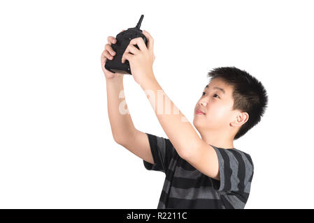 Asian boy holding radio remote control (controlling handset) for helicopter, drone or plane, studio shot isolated on white background. Stock Photo