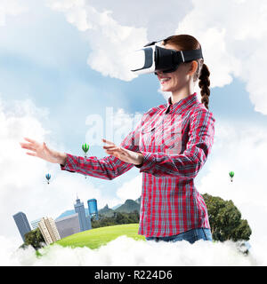 Girl in checked shirt wearing VR glasses experiencing another re Stock Photo