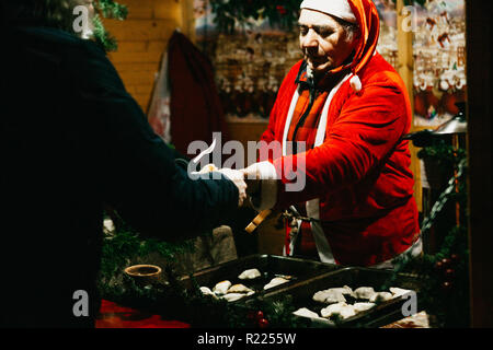 Warsaw, December 25, 2017: A seller dressed as Santa Claus sells fast food at a traditional Christmas night market in Warsaw. Stock Photo