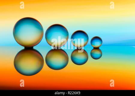 An abstract row of  four fortune teller glass ball / balls / lensball / lensballs / sphere / spheres in a row with colourful background Stock Photo