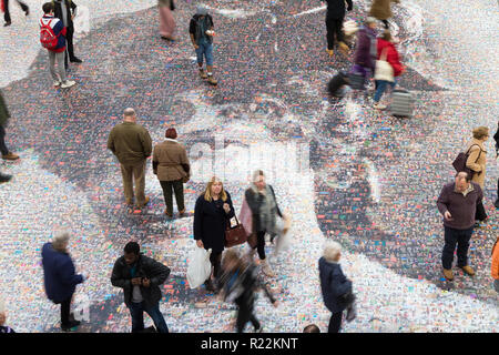Birmingham, UK. 16th November, 2018. A large-scale mosaic portrait of sufragette Hilda Burkitt is on show on the concourse floor of New Street station, Birmingham. The 20 metre portrait is made up of 3,724 selfie photographs and other photographs of women sent in from all over the UK. The project, called Face of Suffrage, is deisgned by artist Helen Marshall. Hilda Burkitt was born in Wolverhampton in 1876, was convicted and jailed for breaking a window in the then Prime Minister's train carriage. Peter Lopeman/Alamy Live News