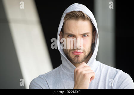 Focused future achievement. Guy bearded attractive casual clothes hooded. Man with bristle concentrated face urban background defocused. Man unshaven guy looks handsome hooded. Concentrated on goal. Stock Photo