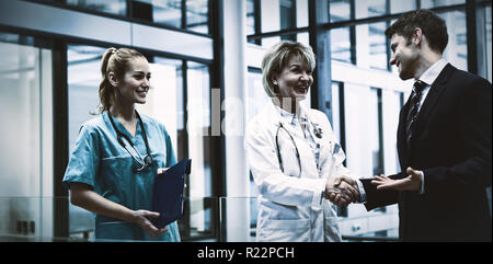 Female doctor shaking hands with businessman Stock Photo