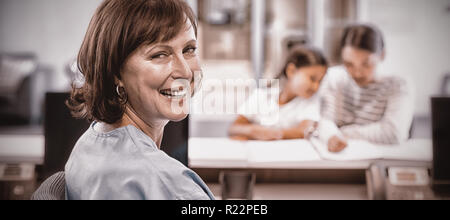 Portrait of smiling nurse sitting at desk Stock Photo