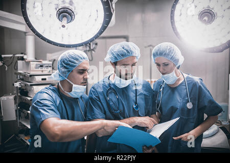 Surgeons discussing patient records in operation room Stock Photo
