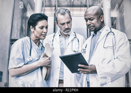 Surgeons and nurse having discussion on digital tablet Stock Photo