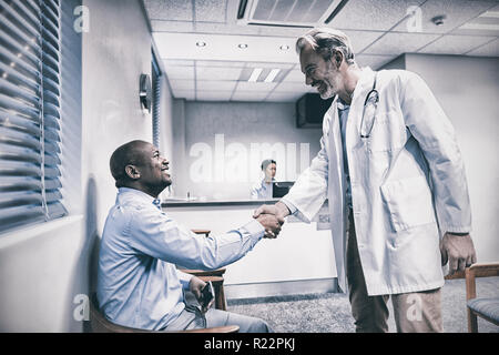 Male doctor shaking hands with patient Stock Photo