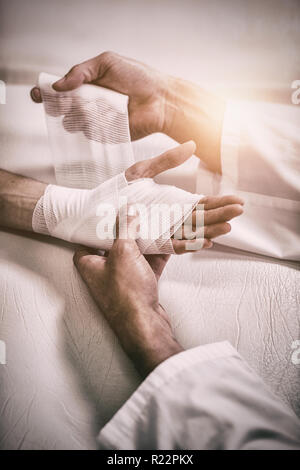 Physiotherapist putting bandage on injured hand of patient Stock Photo