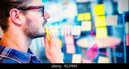 Thoughtful man reading sticky notes on the glass wall Stock Photo