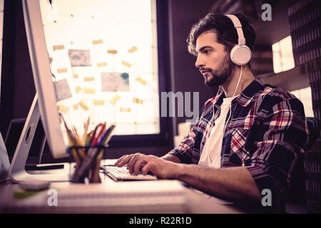 Creative businessman using computer while listening music Stock Photo