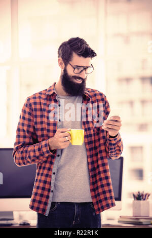 Hipster using smartphone and drinking coffee Stock Photo