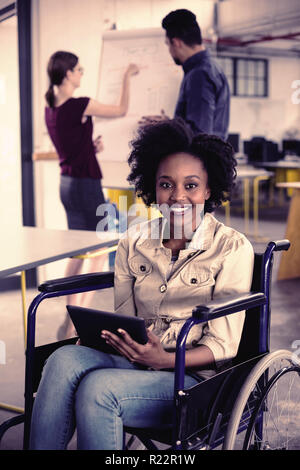 Portrait of smiling disabled business executive in wheelchair using digital tablet Stock Photo