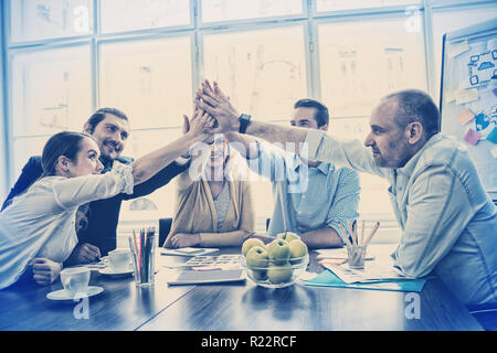Coworkers giving high-five in meeting room Stock Photo