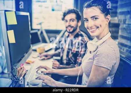 Businesswoman working with male colleague at computer desk Stock Photo