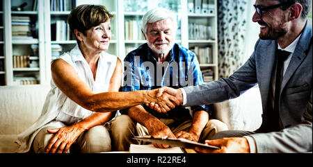 Smiling financial advisor shaking hands with senior woman Stock Photo