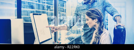 Graphic designer working at desk with colleague Stock Photo