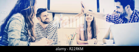 Male colleagues giving high-five in meeting at creative office Stock Photo