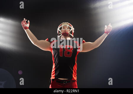 American football player standing against black background Stock Photo