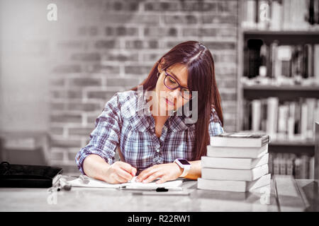 Female student writing notes in library Stock Photo