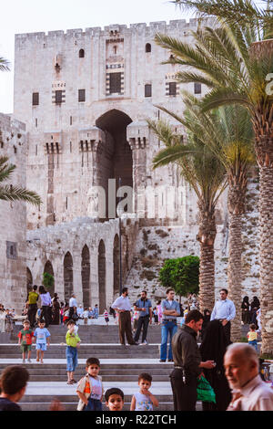 Aleppo, Aleppo Governorate, Syria : People walk past the Citadel of Aleppo, a large medieval fortified palace in the centre of the old city. The site  Stock Photo